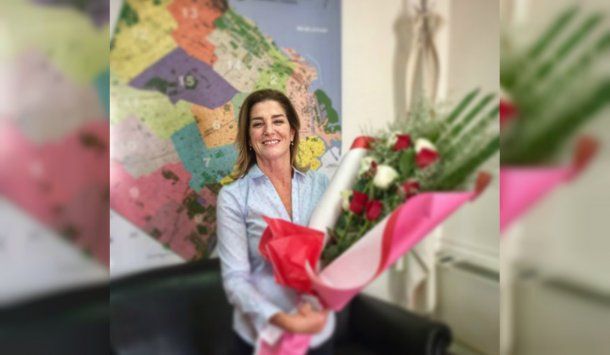 <b>Débora Pérez Volpin, </b>con un ramo de flores y un mapa de la Ciudad de fondo<br>